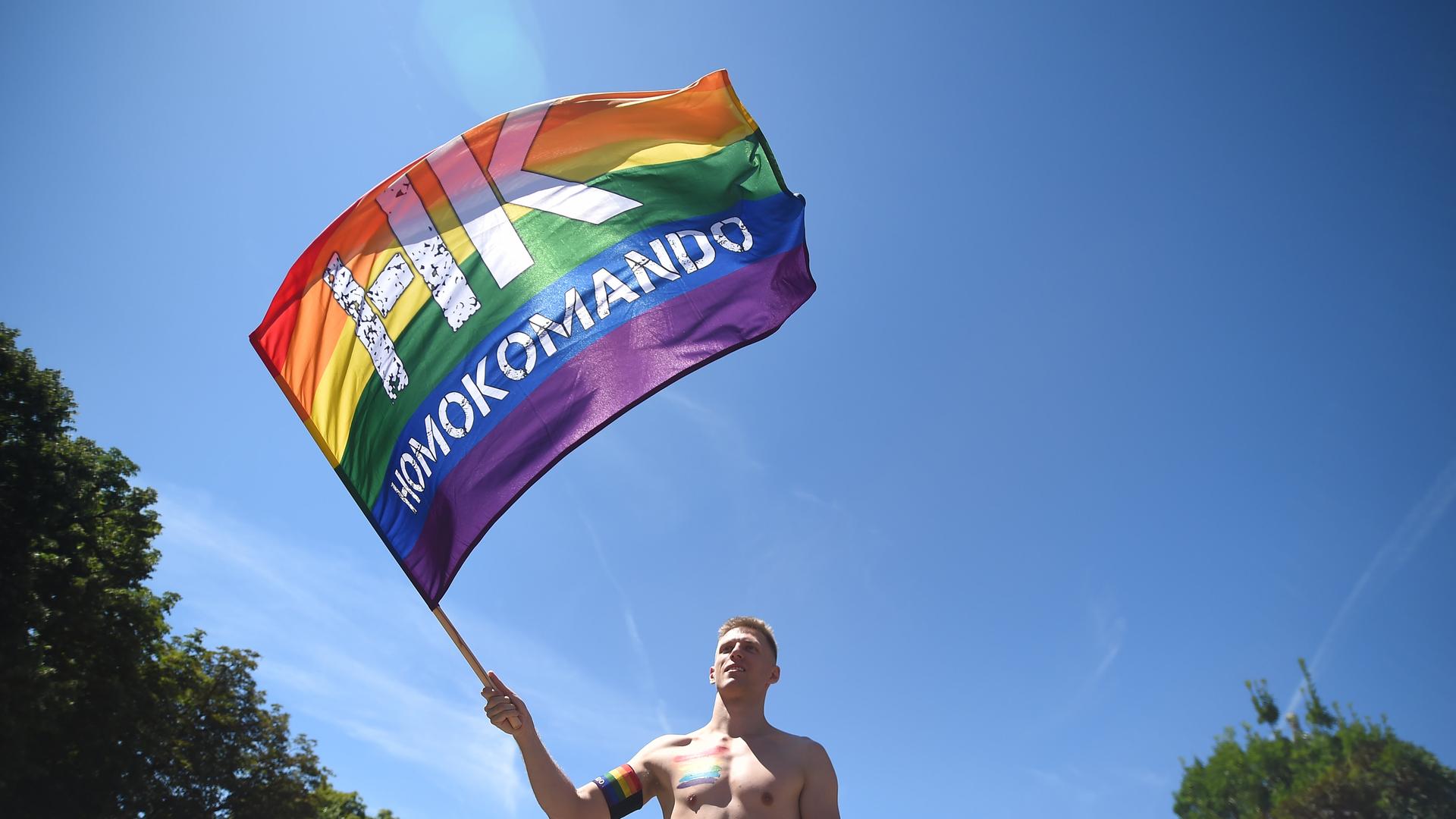 Ein Mann in Budapest hält eine Regenbogenflagge.