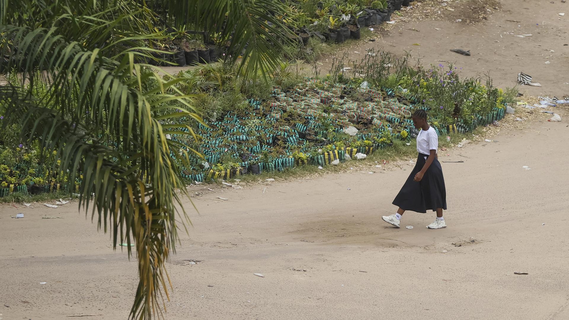 Eine Frau geht in Kinshasa in der Demokratischen Republik Kongo eine Straße entlang. Eine Frau geht in Kinshasa in der Demokratischen Republik Kongo eine Straße entlang.