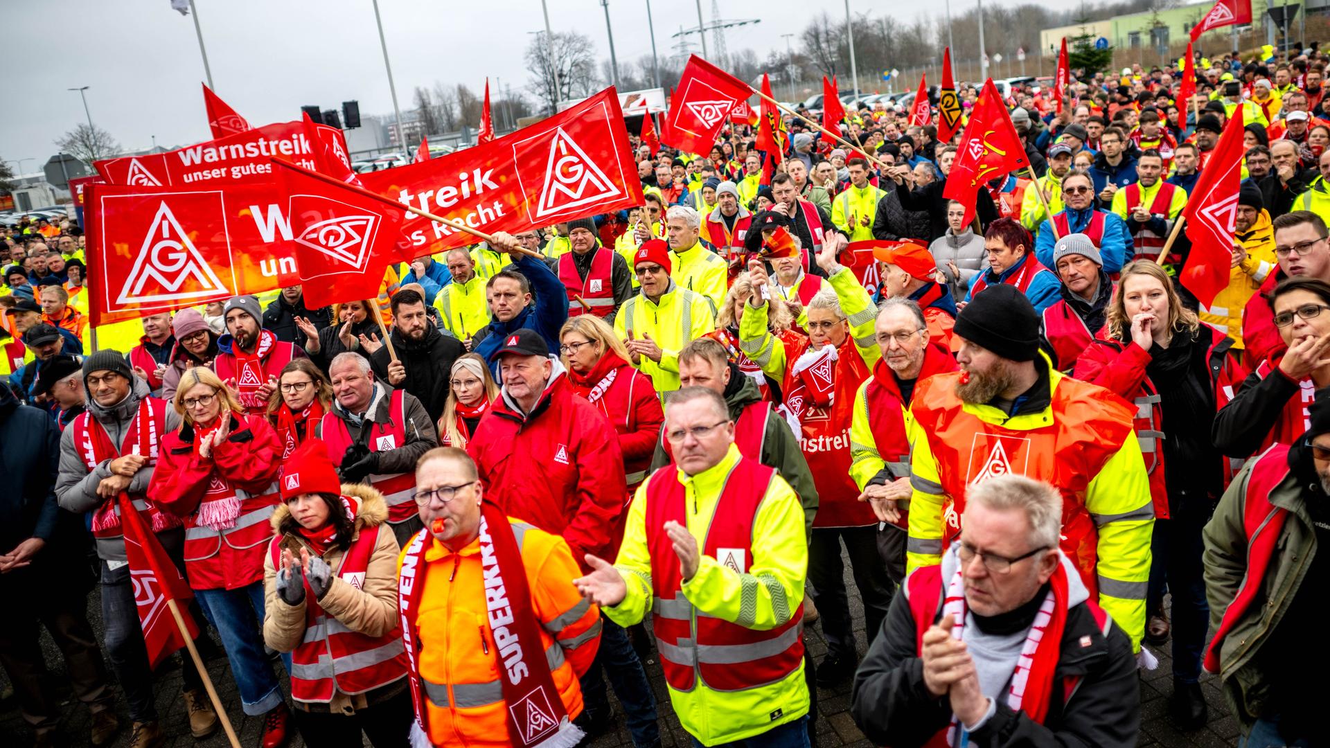 VW-Mitarbeiter bei einer Kundgebung am Werk in Emden. Im Hintergrund: Flaggen der Gewerkschaft IG Metall.