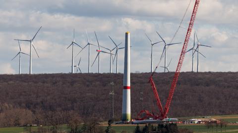Zahlreiche Windkraftanlagen sind am 17.03.2025 in einem Windpark bei Borchen Etteln (Nordrhein-Westfalen) zu sehen, während im Vordergrund eine neue Windkraftanlage aufgebaut wird.