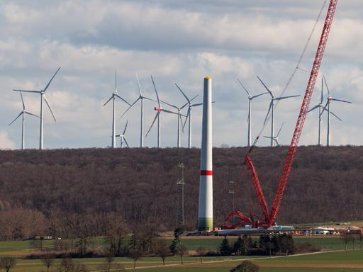 Zahlreiche Windkraftanlagen sind am 17.03.2025 in einem Windpark bei Borchen Etteln (Nordrhein-Westfalen) zu sehen, während im Vordergrund eine neue Windkraftanlage aufgebaut wird.
