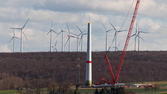 Zahlreiche Windkraftanlagen sind am 17.03.2025 in einem Windpark bei Borchen Etteln (Nordrhein-Westfalen) zu sehen, während im Vordergrund eine neue Windkraftanlage aufgebaut wird.