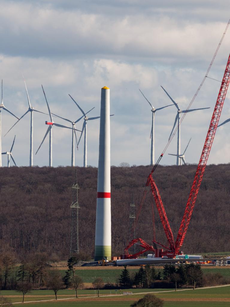 Zahlreiche Windkraftanlagen sind am 17.03.2025 in einem Windpark bei Borchen Etteln (Nordrhein-Westfalen) zu sehen, während im Vordergrund eine neue Windkraftanlage aufgebaut wird.