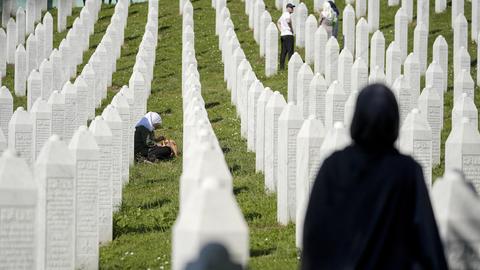Menschen trauern auf dem Friedhof an der Gedenkstätte in Potocari.
      