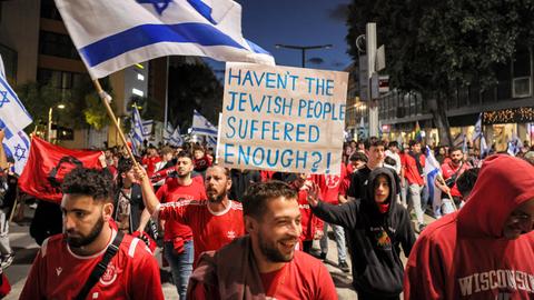Demonstranten schwenken israelische Flaggen und halten Plakate hoch.