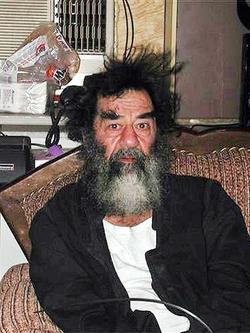 Der irakische Präsident Saddam Hussein sitzt auf einer Coach nach seiner Festnahme durch US-Truppen am 14. Dezember 2003. Der irakische Präsident Saddam Hussein sitzt auf einer Coach nach seiner Festnahme durch US-Truppen am 14. Dezember 2003.