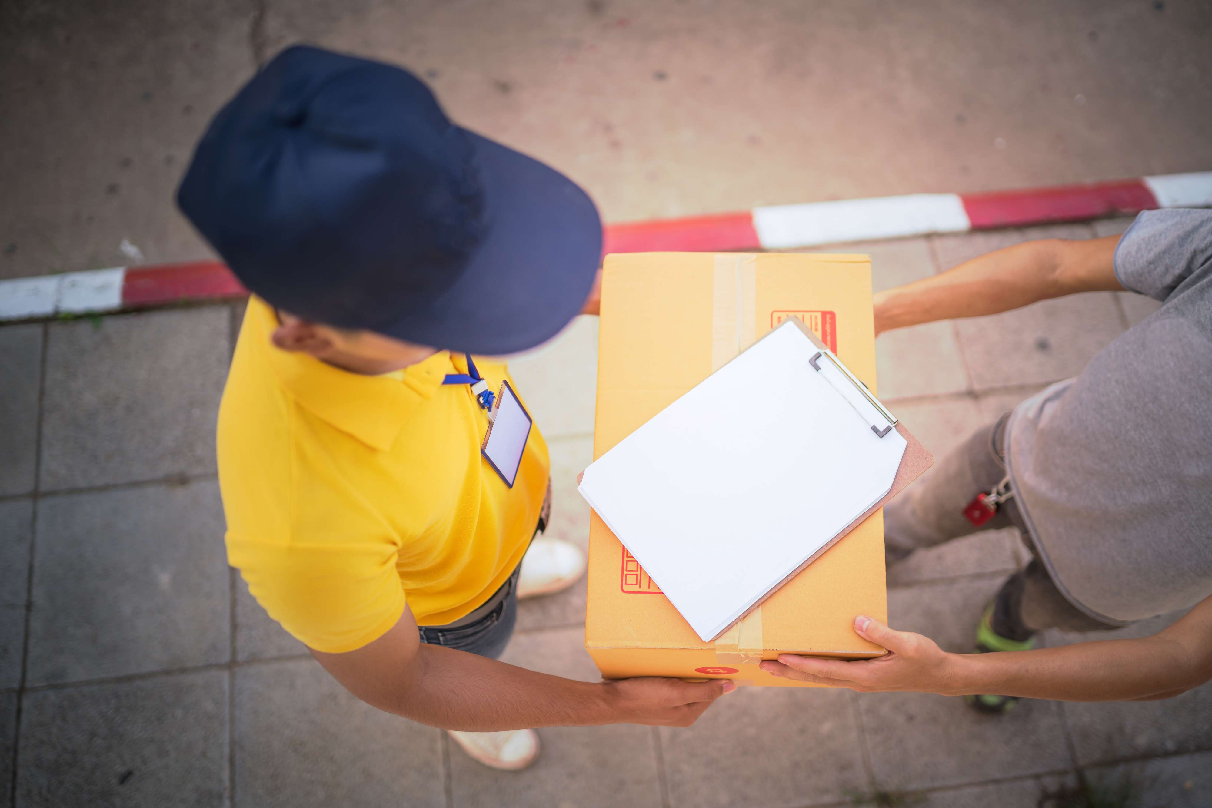 Im direkten Gespräch mit seiner Kundschaft begreift sich Paketzusteller Joël als Lebenshelfer. Zu sehen: Aufnahme von oben -  ein Paketzusteller überreicht ein Paket. 