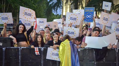Menschen halten Plakate in die Höhne bei einer Demonstration in Tiflis. 
