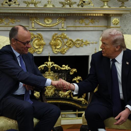 Bundeskanzler Merz und Präsident Trump sitzen nebeneinander auf zwei Sesseln und geben sich die Hand.