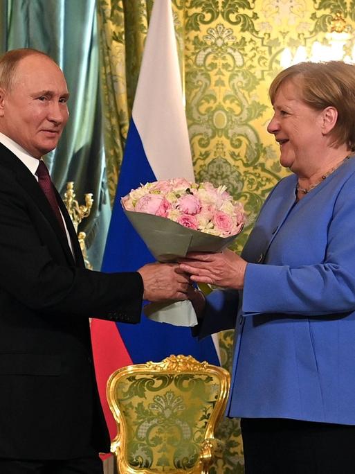 Angela Merkel bekommt einen Blumenstrauß von Wladimir Putin