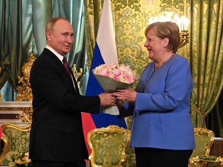 Angela Merkel bekommt einen Blumenstrauß von Wladimir Putin