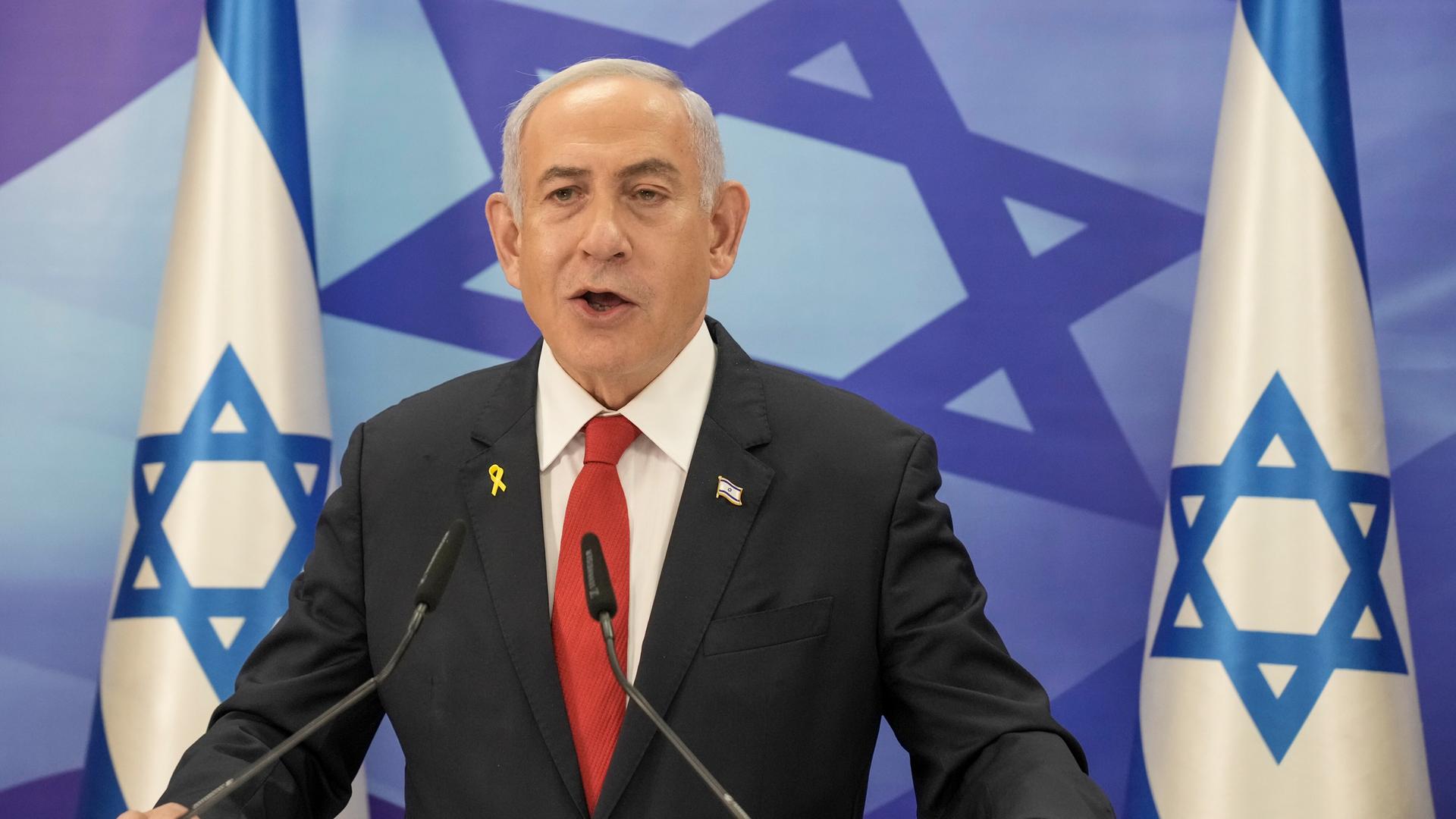 Benjamin Netanyahu am Rednerpult vor der israelischen Flagge.