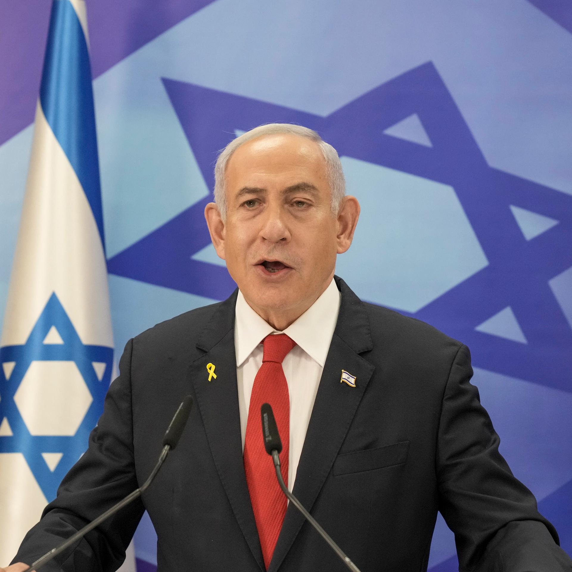 Benjamin Netanyahu am Rednerpult vor der israelischen Flagge.