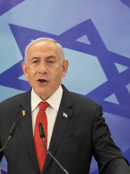 Benjamin Netanyahu am Rednerpult vor der israelischen Flagge.