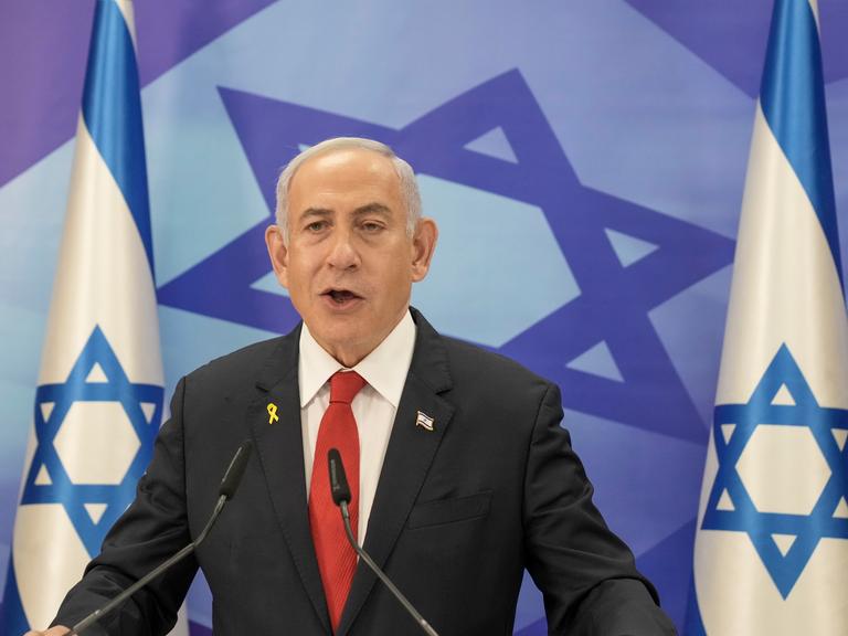 Benjamin Netanyahu am Rednerpult vor der israelischen Flagge.