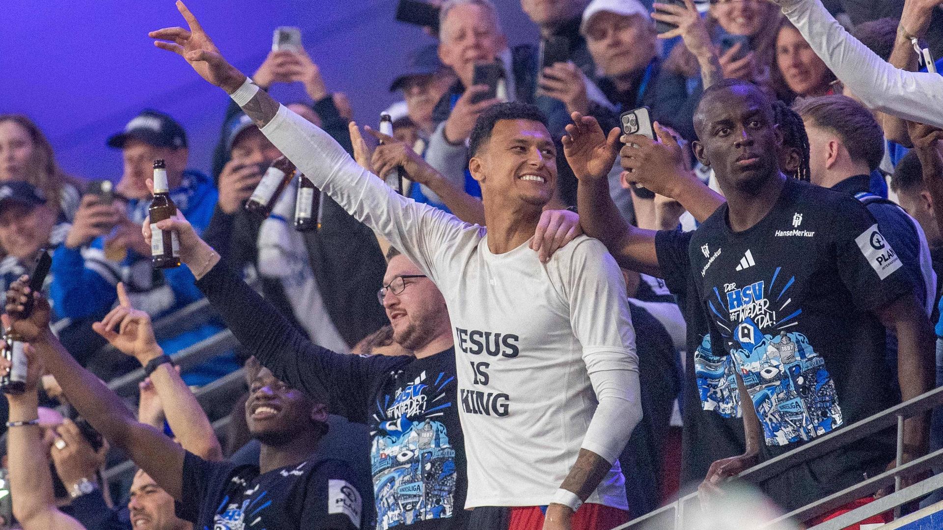 Spieler des HSV feiern im Mai den Aufstieg in die 1. Bundesliga. In der Mitte ist Davie Selke zu sehen, der als einziger ein auffällig weißes T-Shirt trägt. Darauf steht in schwarzen Buchstaben: "Jesus is king" (Jesus ist König). Spieler des HSV feiern im Mai den Aufstieg in die 1. Bundesliga. In der Mitte ist Davie Selke zu sehen, der als einziger ein auffällig weißes T-Shirt trägt. Darauf steht in schwarzen Buchstaben: "Jesus is king" (Jesus ist König).