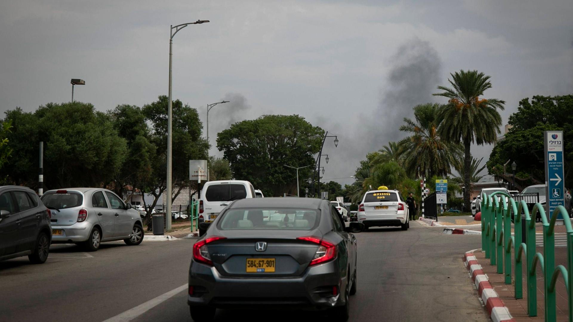 Blick auf eine Straße mit Autos. Am Horizont sieht man eine Rauchwolke.