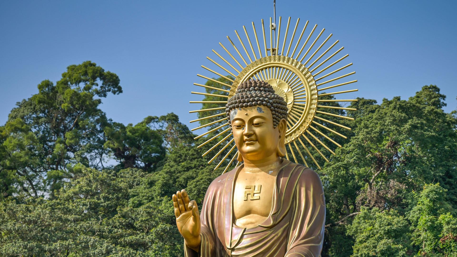 Eine große Buddhastatue steht in Taiwan vor blauem Himmel und tiefgrünen Baumkronen. Eine große Buddhastatue steht in Taiwan vor blauem Himmel und tiefgrünen Baumkronen.