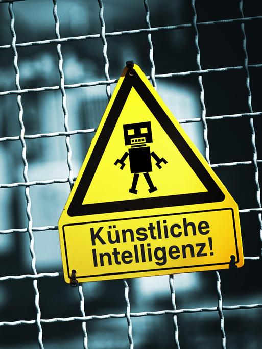 An einem Tor hängt ein Warnschild mit einer Roboterfigur, darunter steht "Künstliche Intelligenz" 