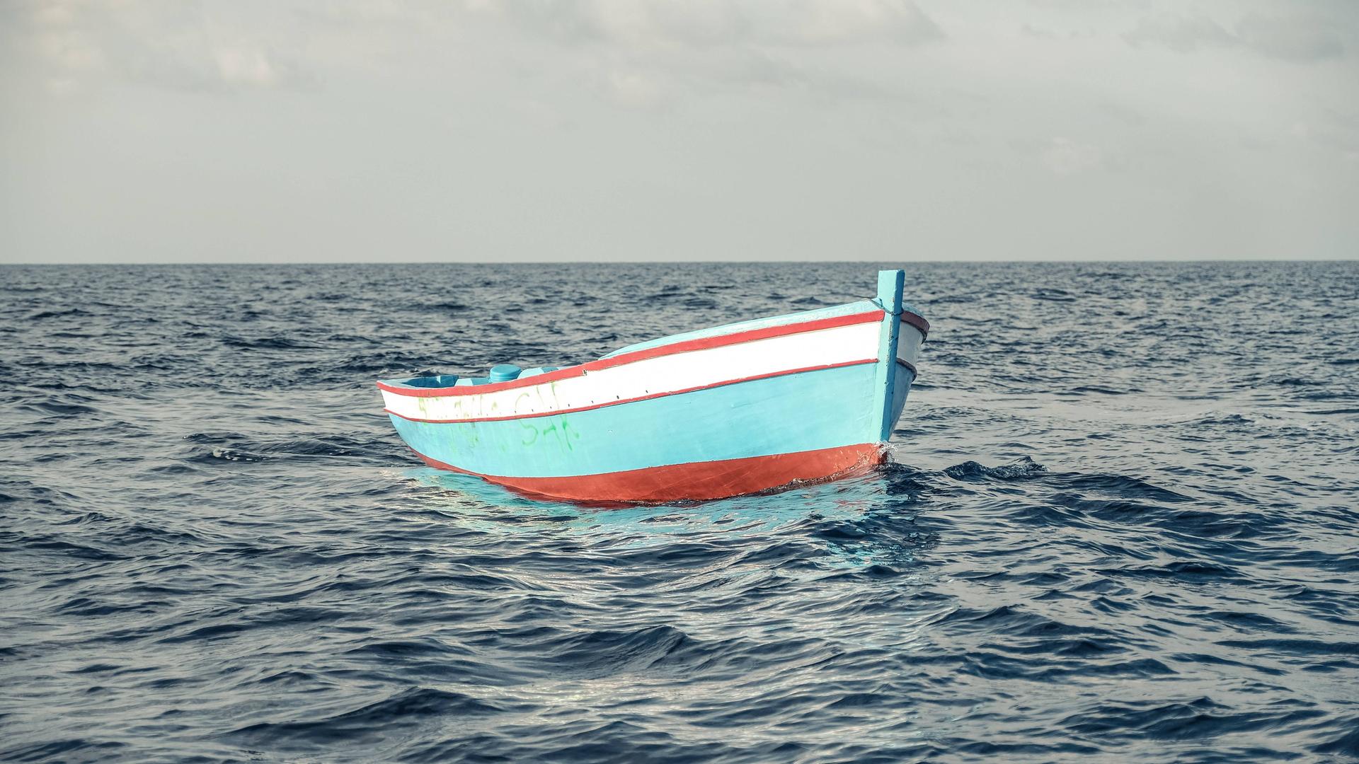 Ein leeres, türkises Flüchtlingsboot aus Holz treibt westlich von Tripolis in Internationalen Gewässern.
