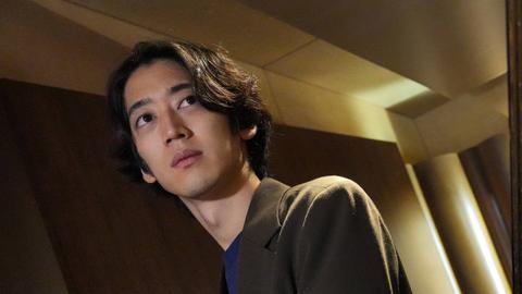 Der japanische Pianist ist schräg über einen Flügel hinweg mit schrägen Perspektiven aufgenommen.