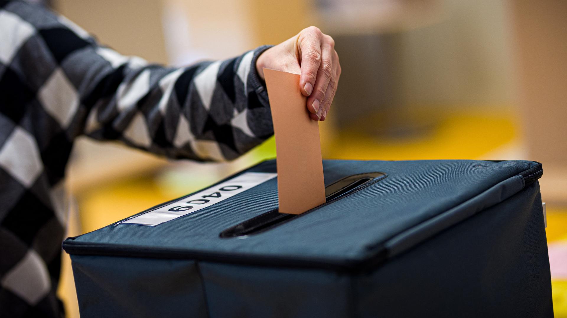 Eine Wählerin wirft ihren Stimmzettel in eine Wahlurne. 