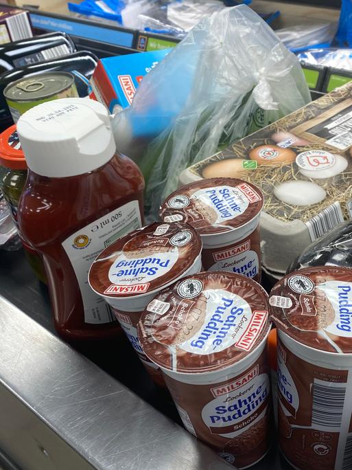 Verschiedene Lebensmittel liegen auf einem Kassenband an einer Supermarktkasse.