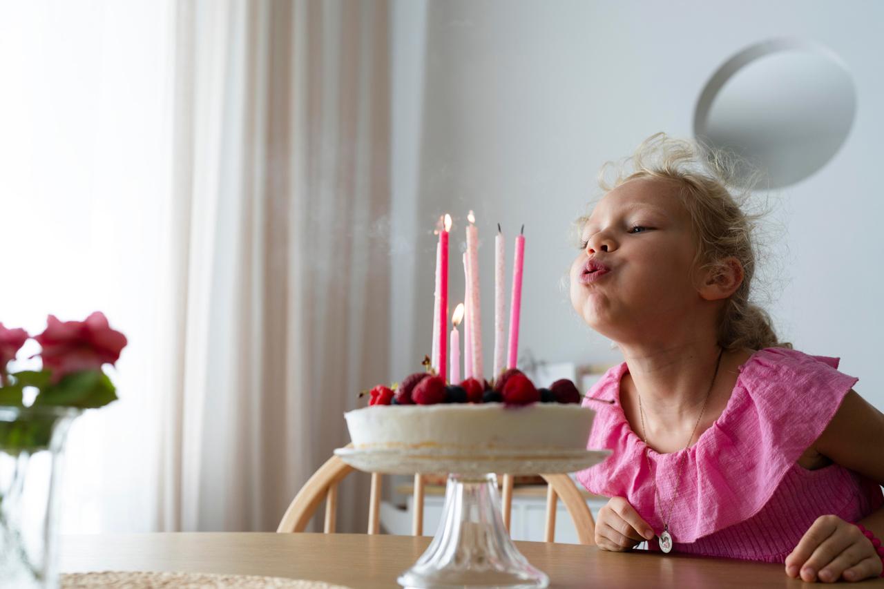 Ein Mädchen bläst Kerzen auf der Geburtstagstorte aus. 
