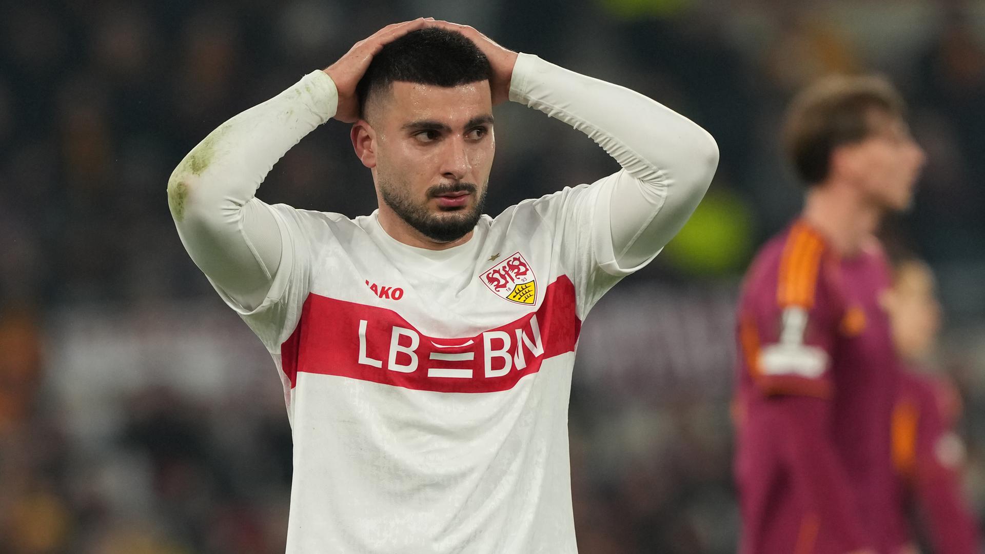 Undav hält beide Hande überm Kopf und blickt enttäuscht zur Seite. Dahinter unscharf zwei Spieler des AS Rom. 