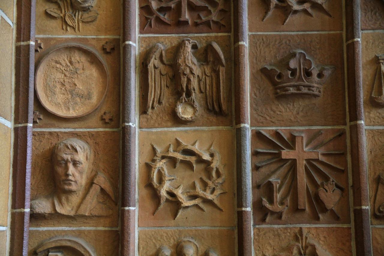 Terrakotten in der Martin-Luther-Gedächtniskirche Berlin zeigen ein Kreuz, eine Krone, einen Reichsadler und andere Symbole.