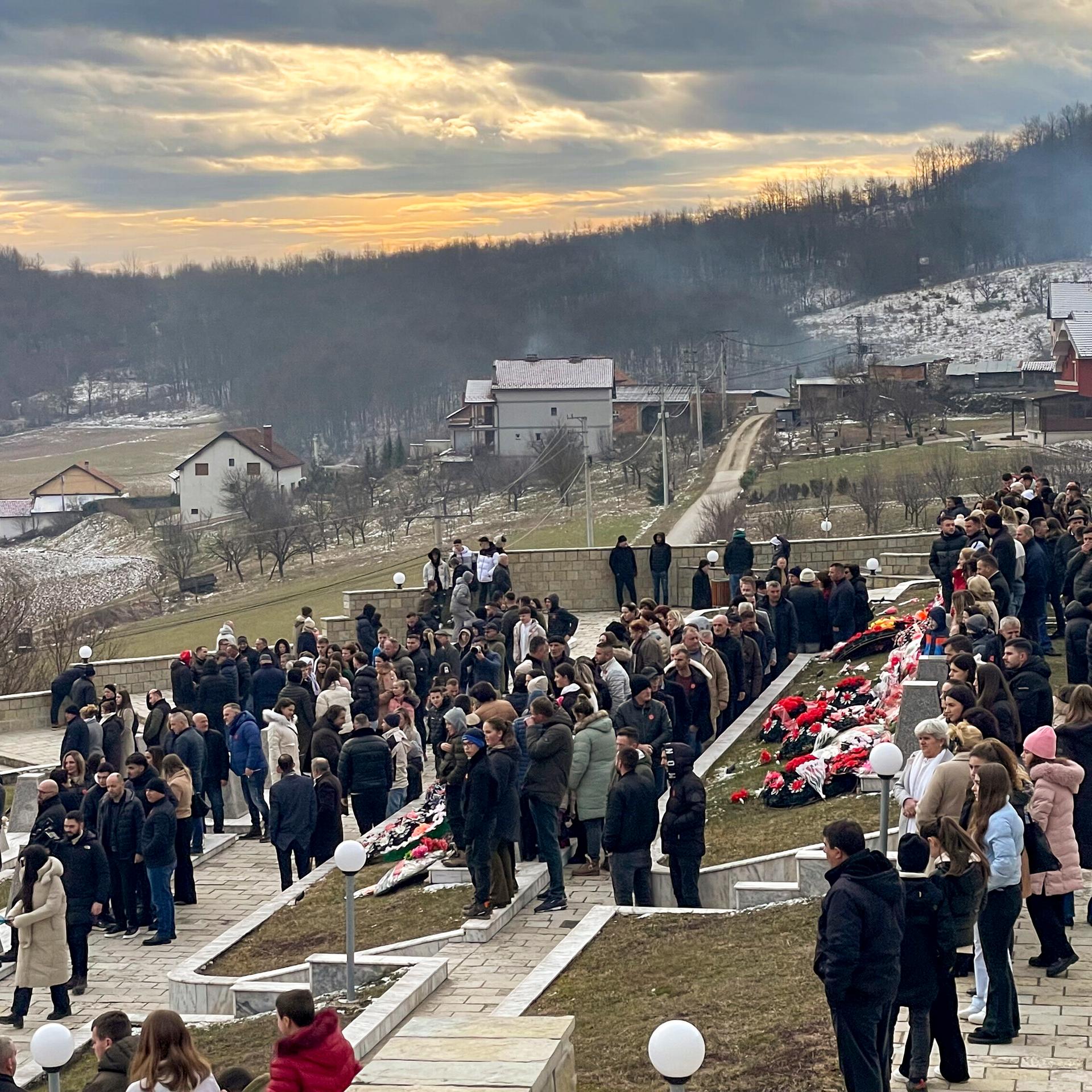Menschen gehen am Montag, dem 15. Januar 2024, auf einem Friedhof während einer Gedenkveranstaltung für Kosovaren, die 1999 von serbischen Streitkräften in Rečak (Kosovo) getötet wurden. 