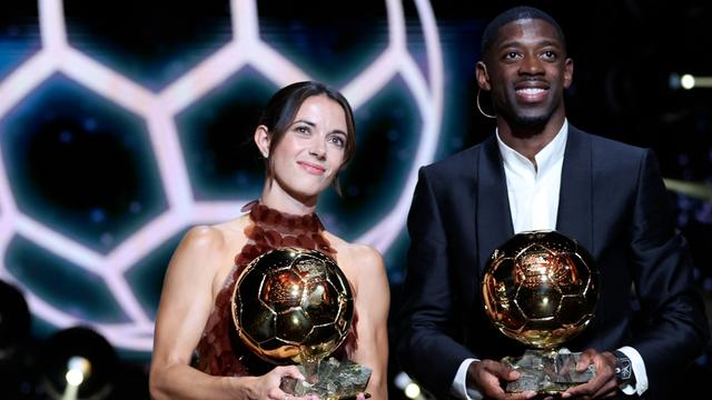 Fußballerin Bonmati und Fußballer Dembele stehen gemeinsam auf der Bühne. Sie halten stolz einen goldenen Fußball vor sich. Das  Das Bild ist von einer Preis-Verleihung aus dem Monat September.