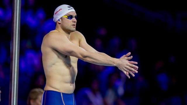 Ein Mann trägt Bade-Hosen und eine Schwimm-Brille. Er hat auch eine Bade-Kappe auf.