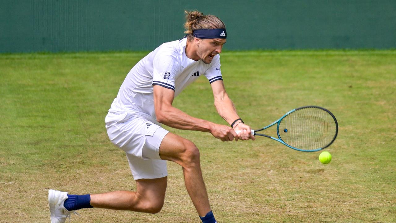 Alexander Zverev trägt Tenniskleidung und hat einen Tennisschläger in der Hand, mit dem er sich nach einem heranfliegenden Ball streckt.