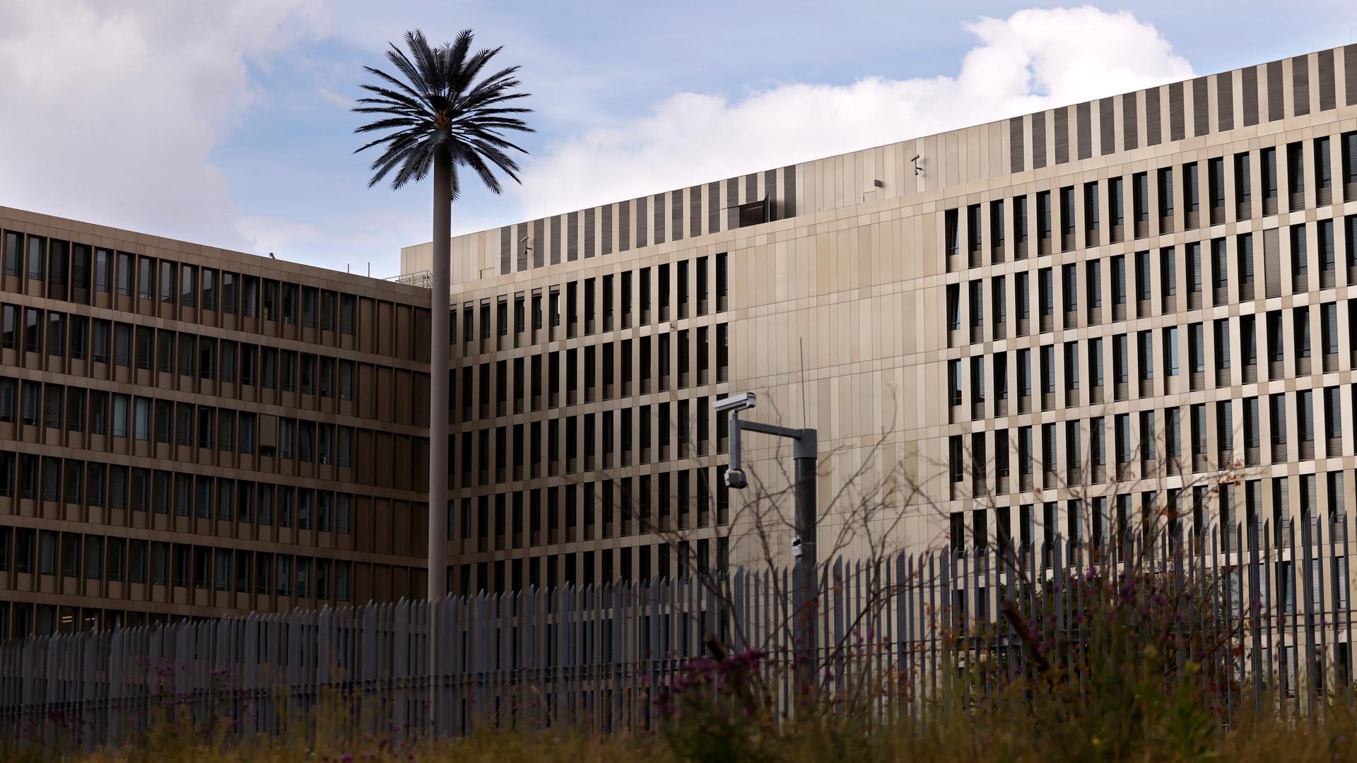 Zu sehen ist der Hauptsitz des Bundesnachrichtendienst (BND) in Berlin. Zu sehen sind ein großer Zaun und eine Überwachungskamera.