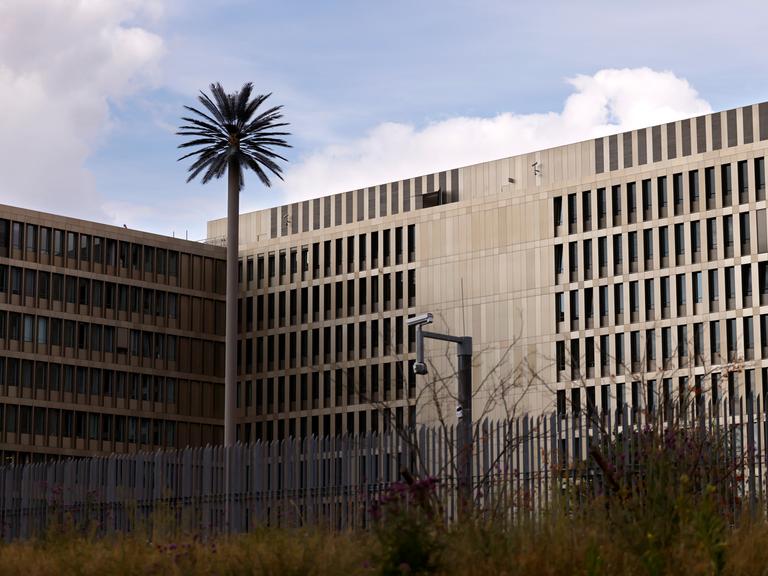 Zu sehen ist der Hauptsitz des Bundesnachrichtendienst (BND) in Berlin. Zu sehen sind ein großer Zaun und eine Überwachungskamera.