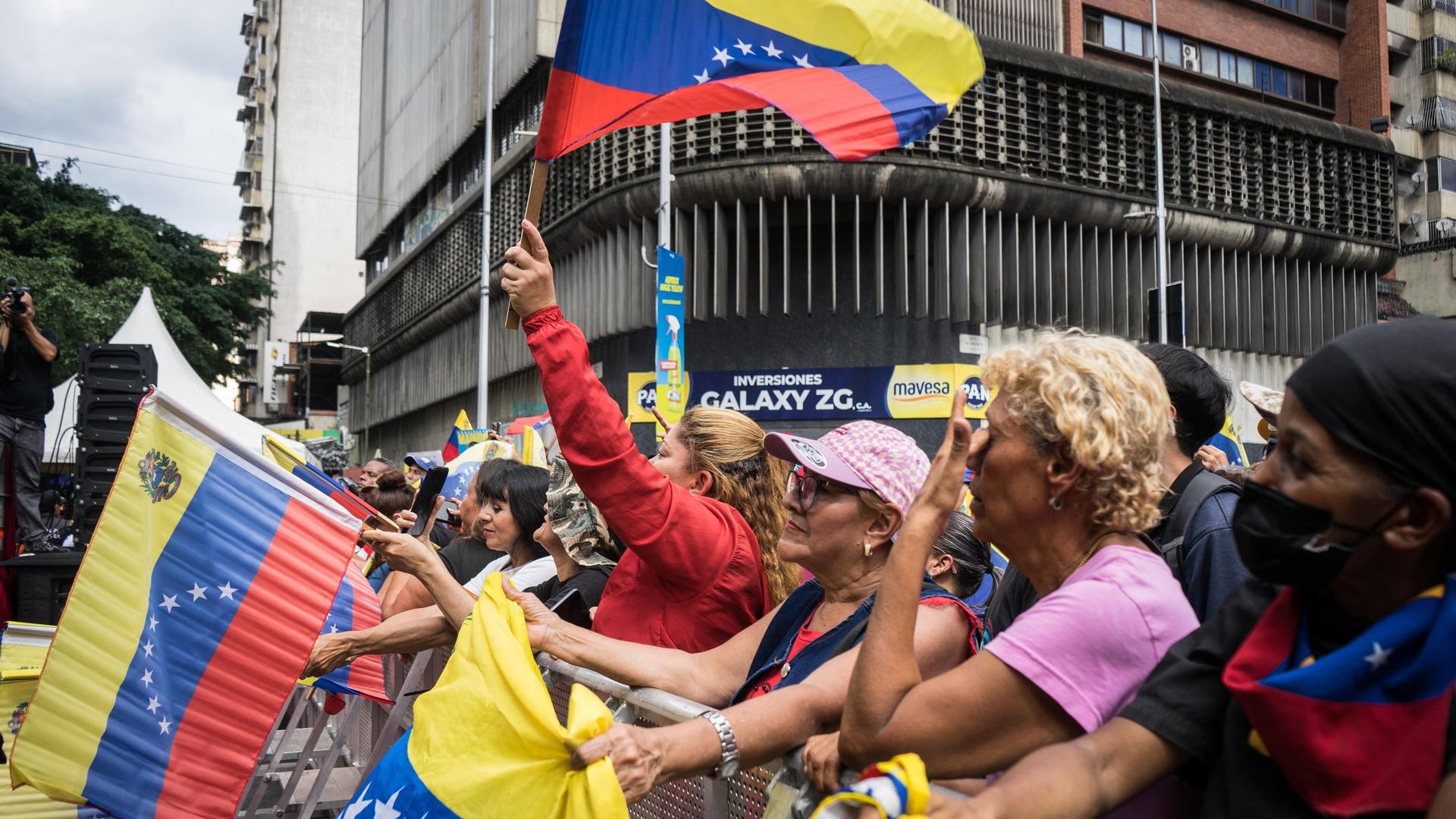 Unterstützerinnen und Unterstützer des bisherigen Staatschefs von Venezuela Nicolás Maduro stehen nach dessen Entführung durch die USA bei einer Demonstration beieinander und schwenken venezolanische Flaggen. 