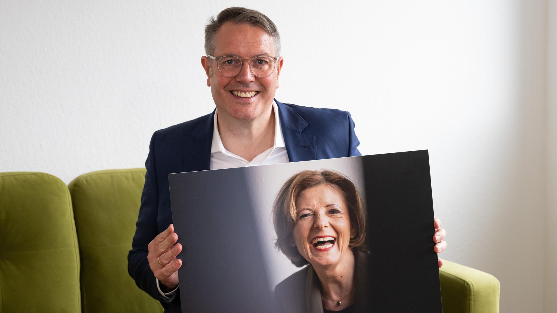 Alexander Schweitzer (SPD), Ministerpräsident von Rheinland-Pfalz bei einem Interview mit der Deutschen Presse Agentur (dpa) in Mainz. Dabei hält er ein Foto seiner Amtsvorgängerin Malu Dreyer (SPD) in den Händen.