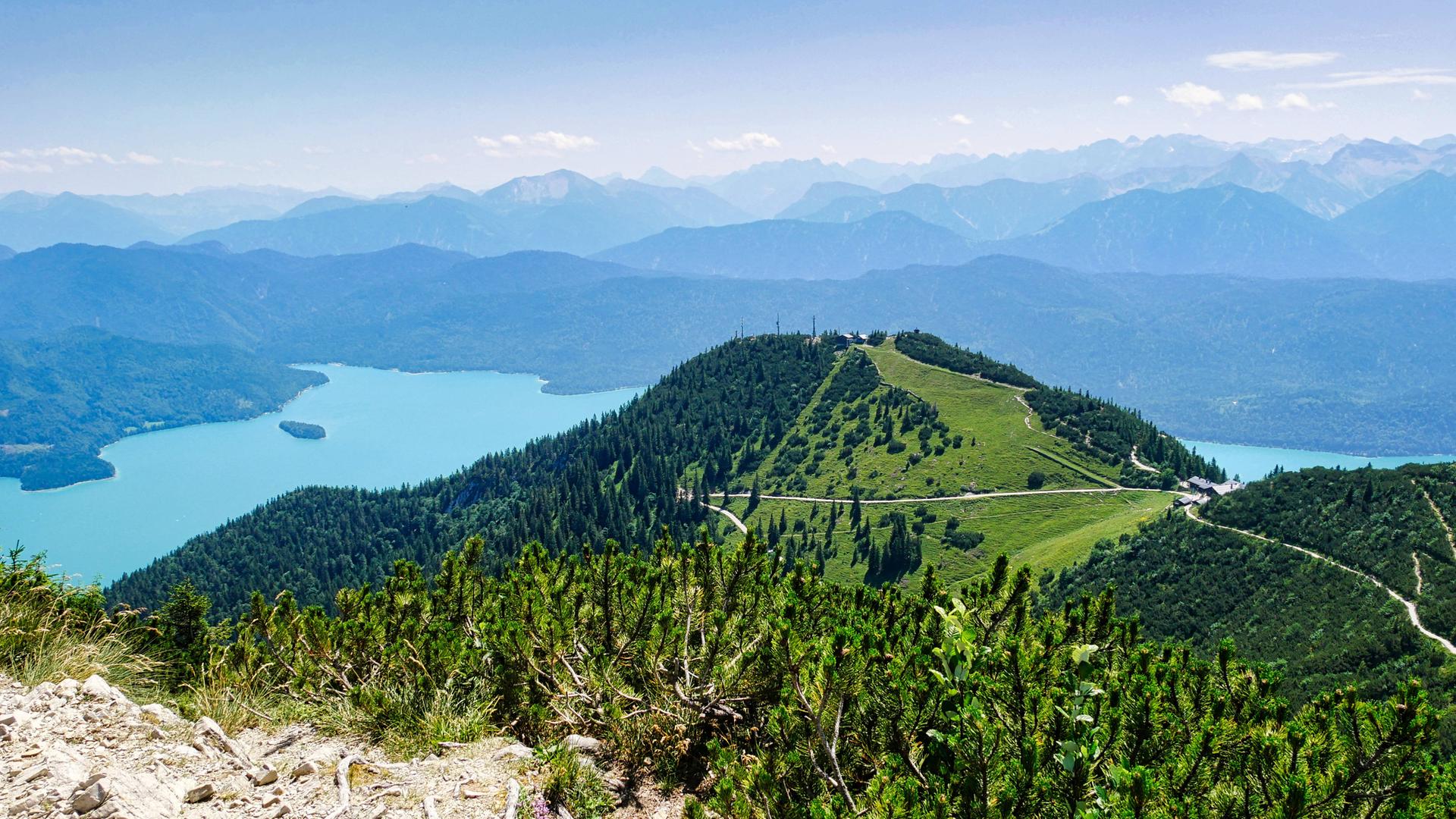 Weiter Panoramablick vom Berg auf eine alpine Seenlandschaft