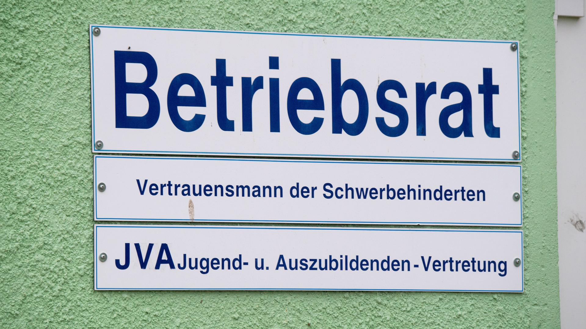 Ein Schild mit der Aufschrift "Betriebsrat - Vertrauensmann der Schwerbehinderten und JVA Jugend- u. Auszubildenden-Vertretung" hängt an einer Fassade