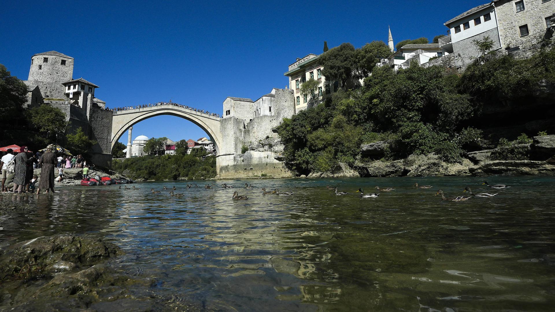 Die Ottoman-era Mostar Bridge in Bosnien-Herzegowina im Hintergrund, davor der Fluss Neretva