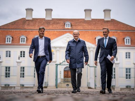 Bundeskanzler Olaf Scholz (SPD, Mitte) kommt zwischen Christian Lindner (FDP, links), Bundesminister der Finanzen, und Robert Habeck (Bündnis 90/Die Grünen, rechts), Bundesminister für Wirtschaft und Klimaschutz, zum Pressestatement bei der Halbzeit-Klausur des Bundeskabinetts auf Schloss Meseberg. 