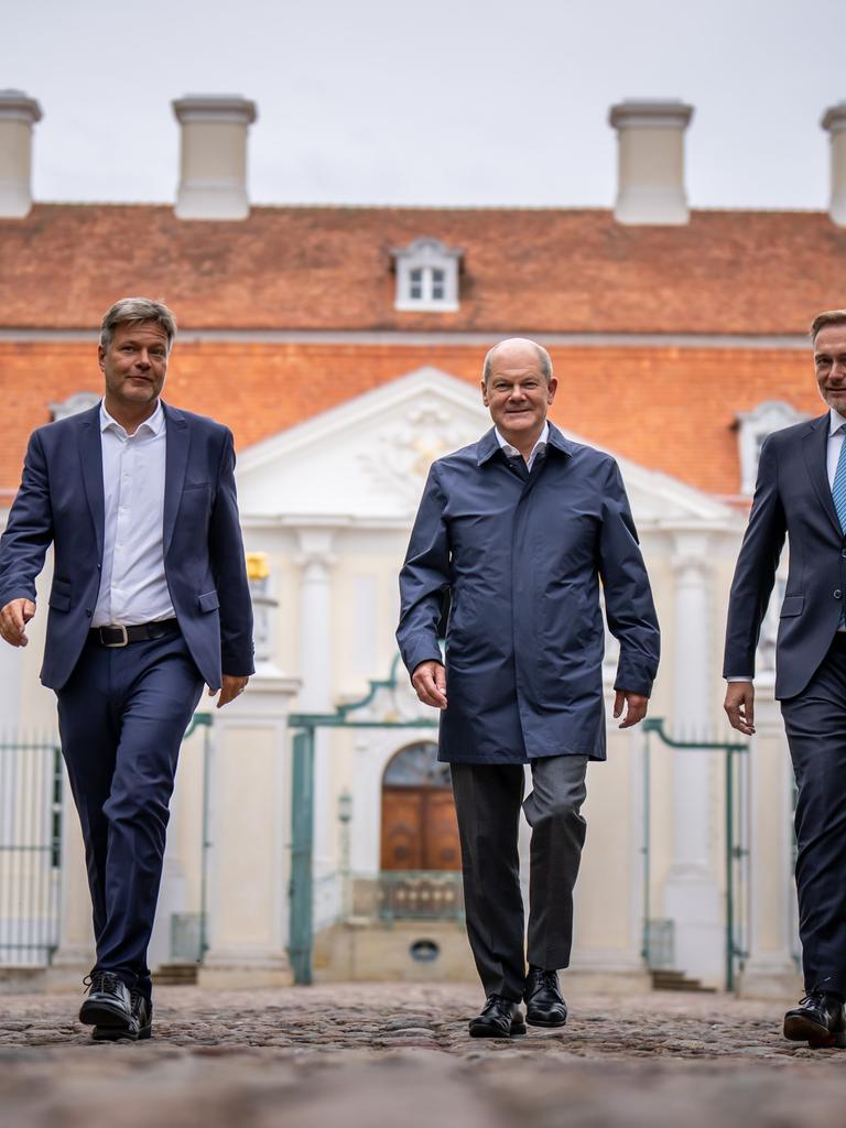 Bundeskanzler Olaf Scholz (SPD, Mitte) kommt zwischen Christian Lindner (FDP, links), Bundesminister der Finanzen, und Robert Habeck (Bündnis 90/Die Grünen, rechts), Bundesminister für Wirtschaft und Klimaschutz, zum Pressestatement bei der Halbzeit-Klausur des Bundeskabinetts auf Schloss Meseberg. 