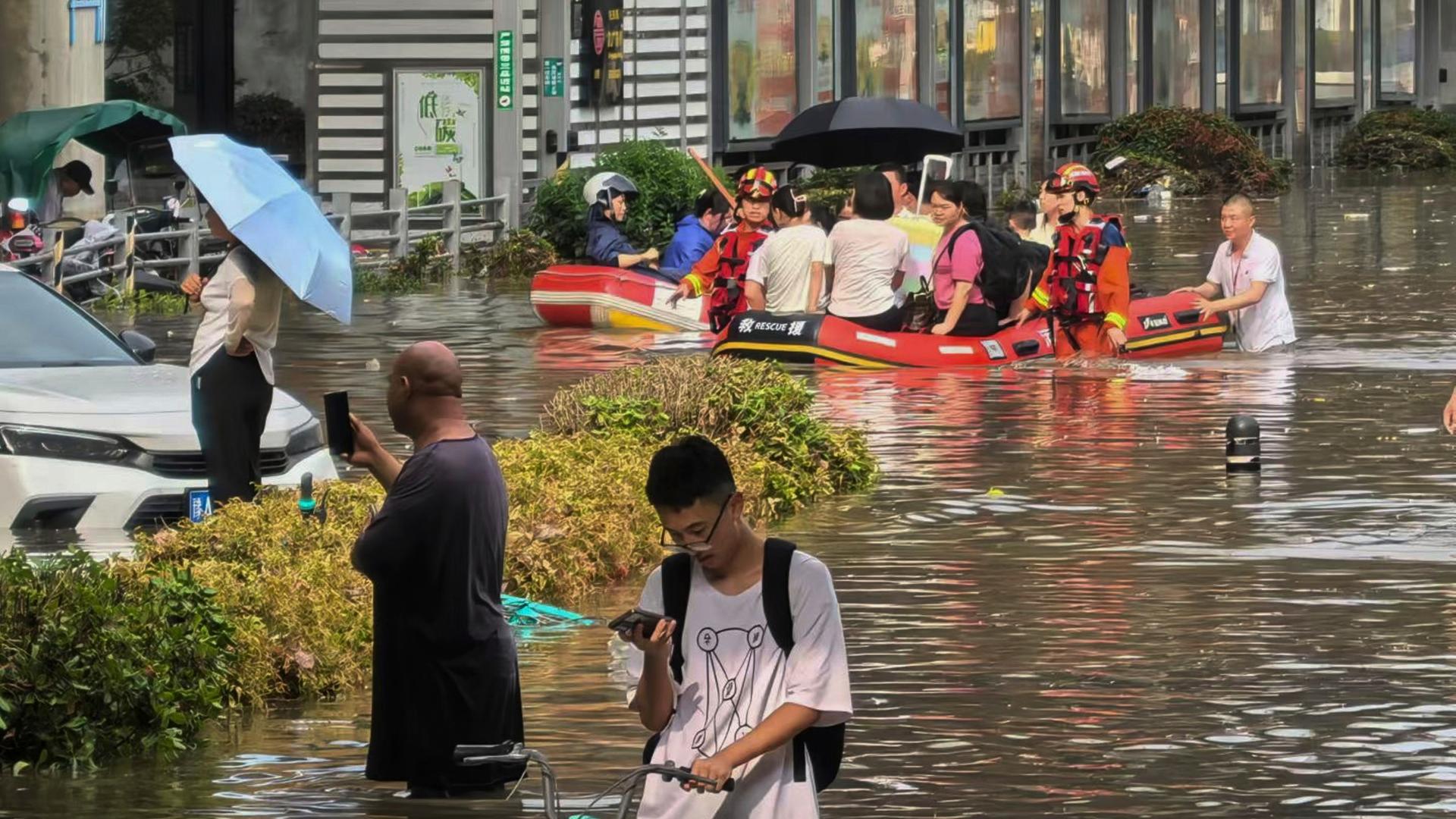 Zhengzhou: Rettungskräfte bringen Menschen nach starken Regenfällen in Schlauchbooten über eine überschwemmte Straße. Zhengzhou: Rettungskräfte bringen Menschen nach starken Regenfällen in Schlauchbooten über eine überschwemmte Straße.