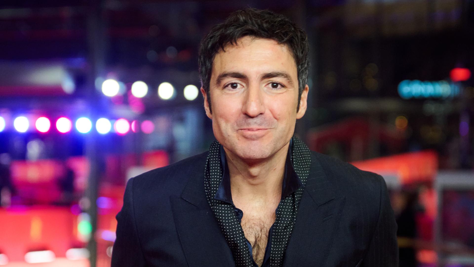 Porträt vonİlker Çatak, dem Regisseur von „Gelbe Briefe“. Er guckt in die Kamera. Er trägt eine schwarze jacke und ein dunkles Hemd.