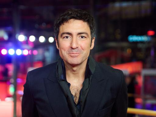 Porträt vonİlker Çatak, dem Regisseur von „Gelbe Briefe“. Er guckt in die Kamera. Er trägt eine schwarze jacke und ein dunkles Hemd.