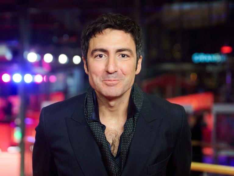 Porträt vonİlker Çatak, dem Regisseur von „Gelbe Briefe“. Er guckt in die Kamera. Er trägt eine schwarze jacke und ein dunkles Hemd.