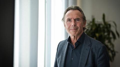 Thomas Druyen trägt ein dunkles Hemd, ein dunkles Sakko und steht vor einem mit Gardinen verhangenen Fenster. Thomas Druyen trägt ein dunkles Hemd, ein dunkles Sakko und steht vor einem mit Gardinen verhangenen Fenster.