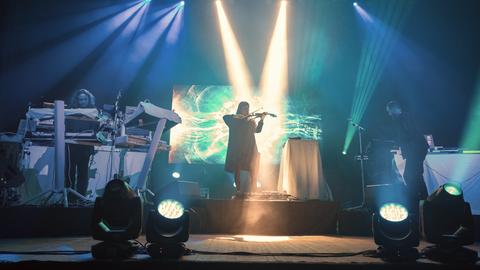 Die drei Mitglieder von Tangerine Dream performen auf einer grün-blau beleuchteten Bühne.