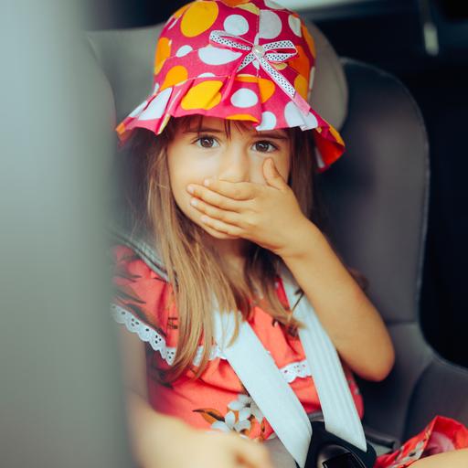 Ein Mädchen bei der Autofahrt hält sich die Hand vor den Mund